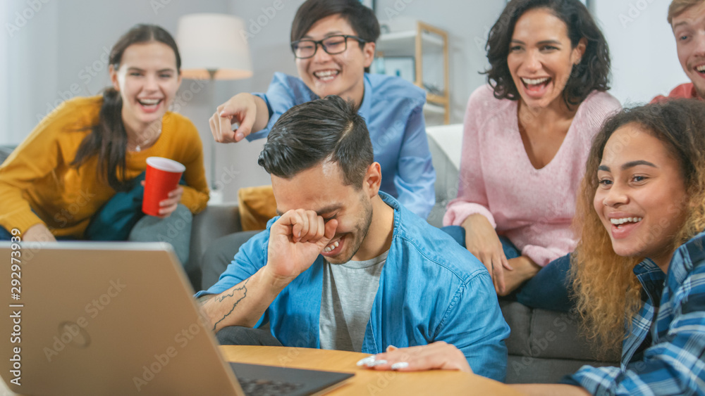 Diverse Group of Friends Use Laptop in the Living Room. Happy Beautiful Girls and Guys Live Streaming or Watching Content. They Have Fun and Laugh. Diverse Group of Friends Use Laptop in the Living Room. Happy Beautiful Girls and Guys Live Streaming or Watching Content. They Have Fun and Laugh.