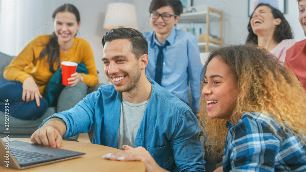 Obraz premium Diverse Group of Friends Use Laptop in the Living Room. Happy Beautiful Girls and Guys Live Streaming or Watching Content. They Have Fun and Laugh.