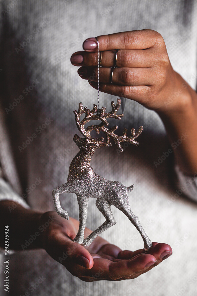 Woman in sweater holding toy deer glass decorative ball in hands, copy space. Christmas, new year