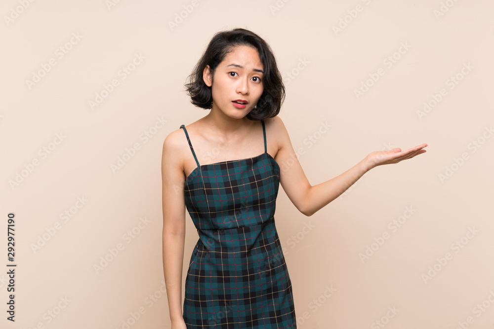 Obraz premium Asian young woman over isolated yellow wall making doubts gesture