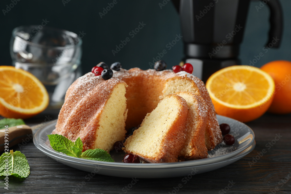 Cake with powdered sugar, berries and mint on wooden background, close up