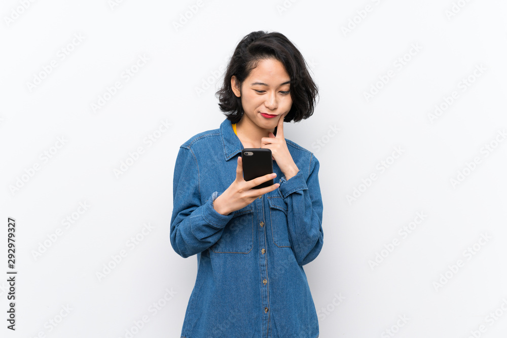 Asian young woman over isolated white background thinking and sending a message Asian young woman over isolated white background thinking and sending a message