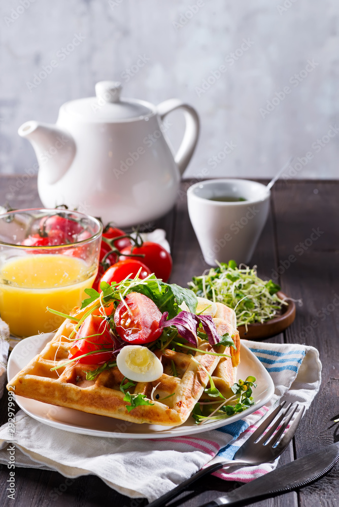 Belgian Waffles with avocado, eggs, micro green and tomatoes with orange juice and tea on wooden table. Perfect breakfast for healthy food or lose weight. Avocado sandwich. Belgian Waffles with avocado, eggs, micro green and tomatoes with orange juice and tea on wooden table. Perfect breakfast for healthy food or lose weight. Avocado sandwich.