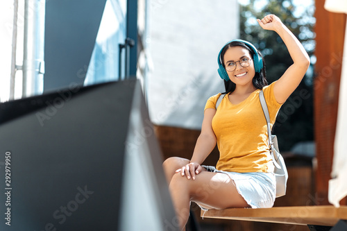 Happy brunette young woman with bright smile dressed in casual clothes listening to music with headphones and smiling.