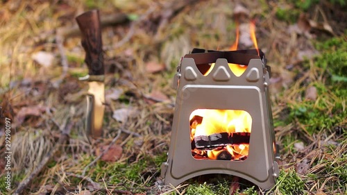 Close up of wood burning folding twig stove in forest background