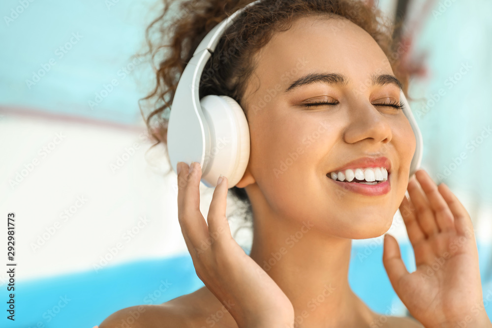 Naklejka premium Beautiful African-American woman listening to music outdoors