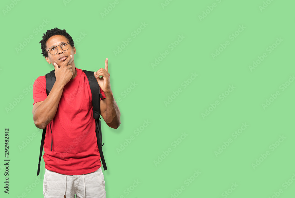 Hesitant young man pointing up with his finger Hesitant young man pointing up with his finger