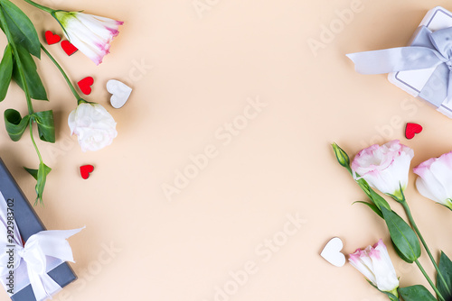 Gift boxes and eustoma flowers for Mothers day or other holidays on beige paper background, top view. Copy space