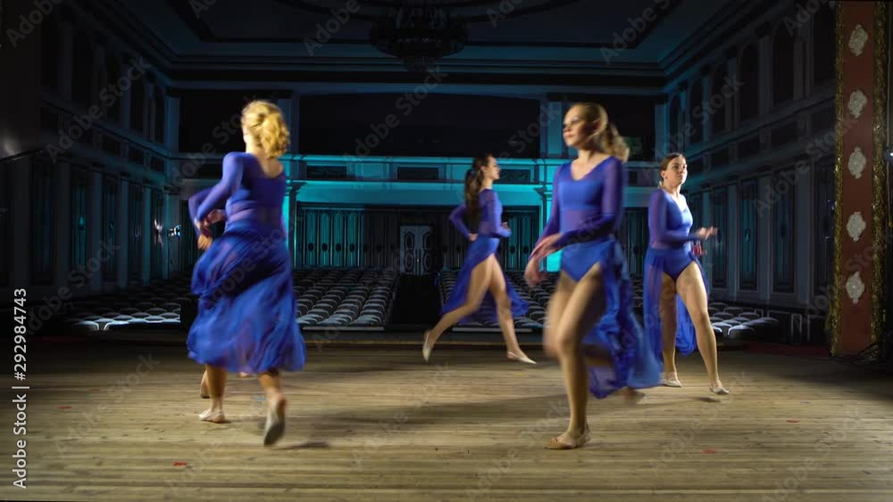 Group young skillful ballerinas dancing modern ballet on the stage of large hall. Girls looking at auditorium. Dress rehearsal before performance. Group young skillful ballerinas dancing modern ballet on the stage of large hall. Girls looking at auditorium. Dress rehearsal before performance.