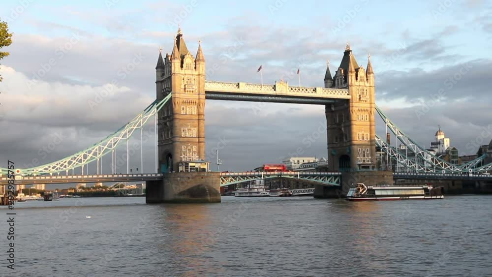Afternoon light on the Tower Bridge in London with a red bus and a water taxi 