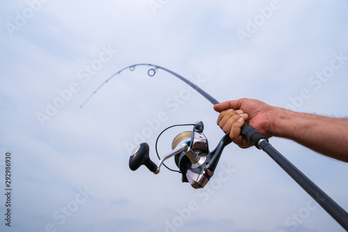 Male hand holding a fishing rod and reel