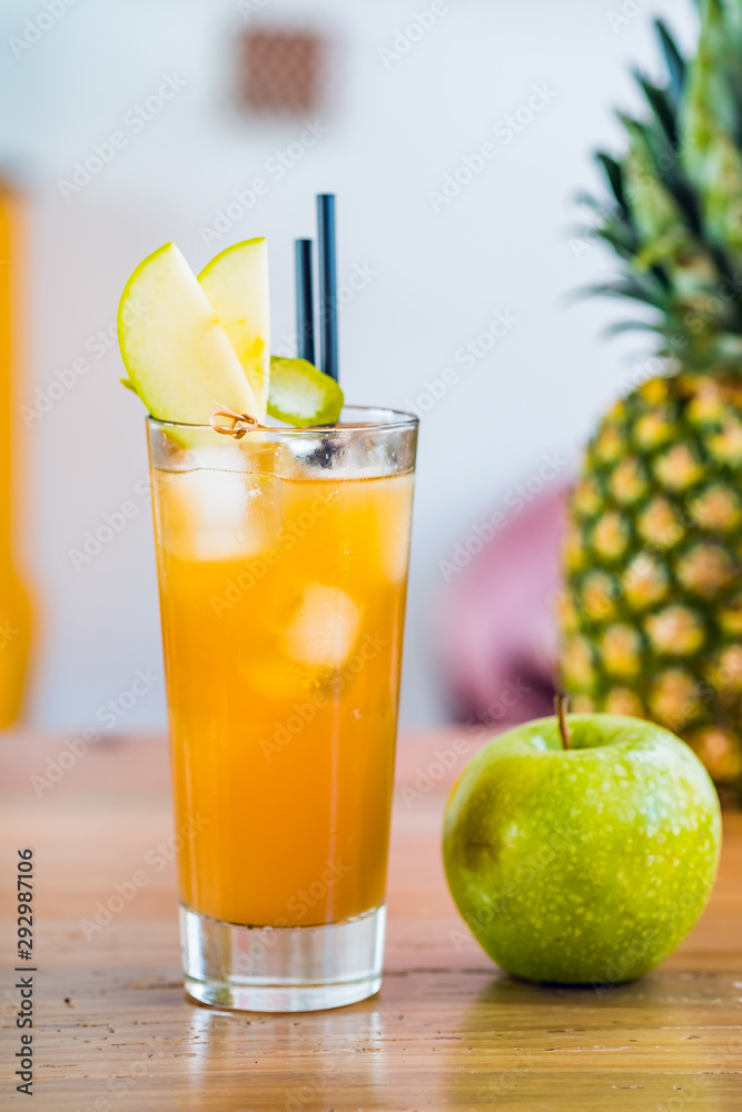 Close-up of orange fresh fruit cocktail drink in a tall glass decorated with apple. Close-up of orange fresh fruit cocktail drink in a tall glass decorated with apple.