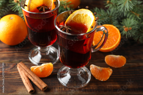 Glasses of tasty mulled wine with orange on wooden background, close up