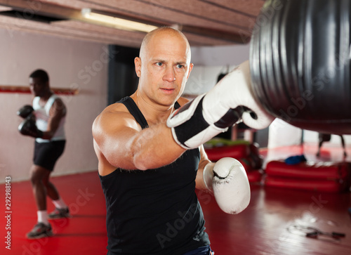 Confident boxer man training on punching bag © JackF