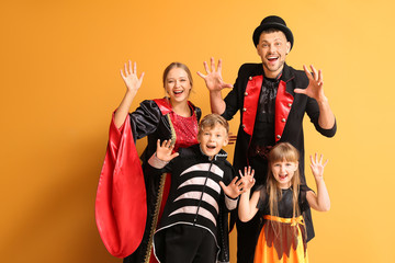 Family in Halloween costumes on color background