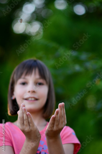 Little girl catching butterfly in the garden with her hands. Girl having fun in the garden catching successfully butterfly only with her hands.