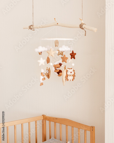 Cute handmade felt mobile on the crib for children. Brown and white colors. Bear, owl, deer, sheep, hedgehog and stars