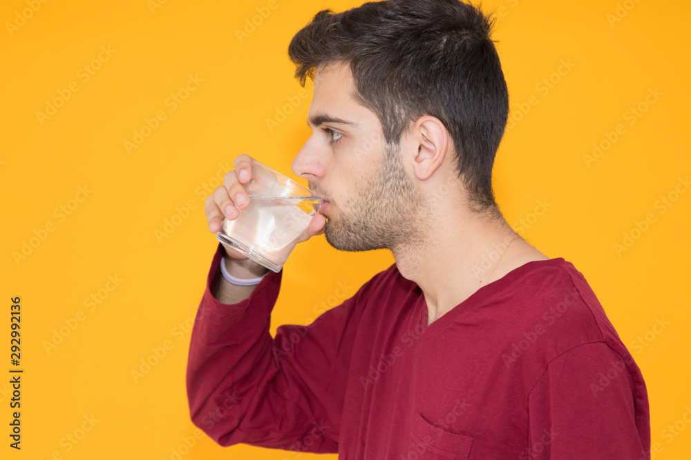 young man drinking water isolated on color background young man drinking water isolated on color background