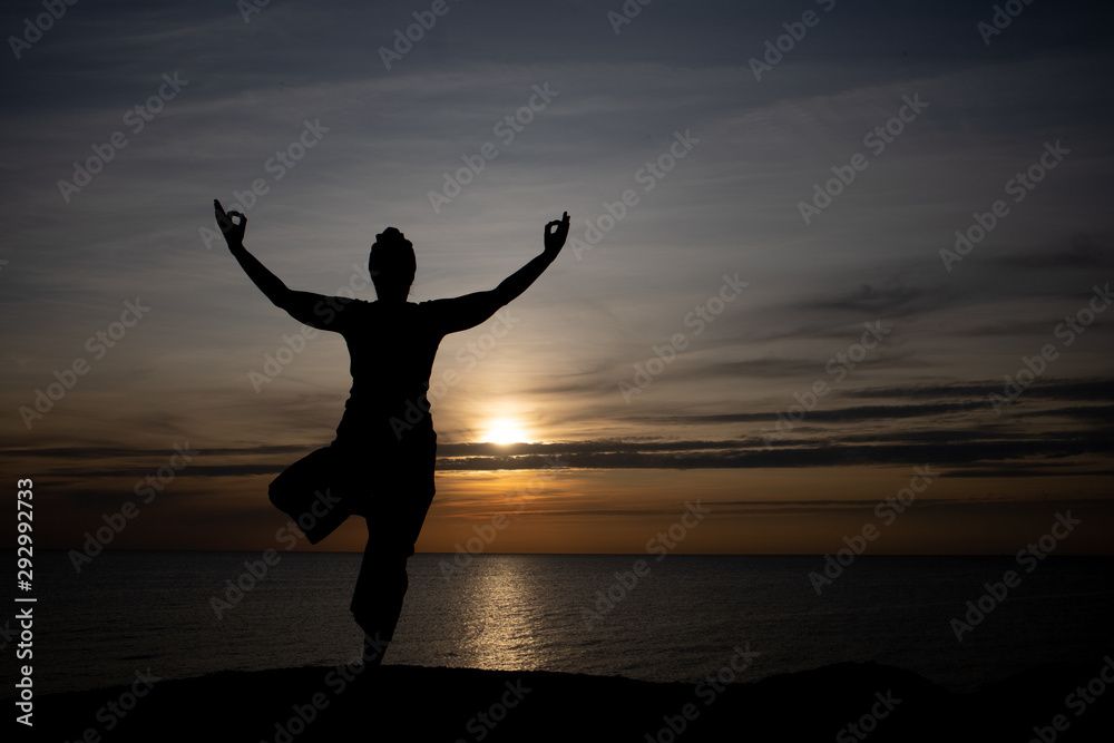 silhouette of woman at sunset, yoga position against the setting sun on the island of Bornholm, Denmark