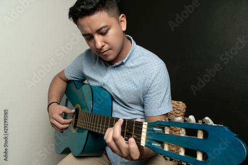 Boy playing acoustic guitar on a bench photo