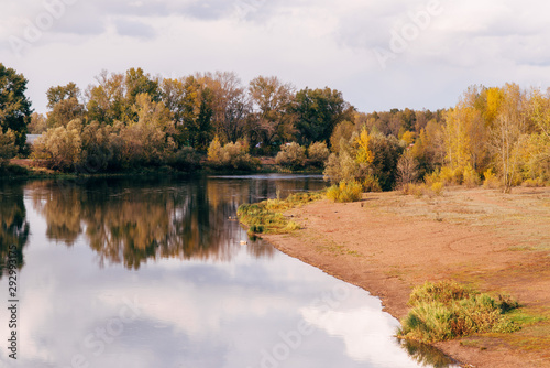 Autumn landscape of beautiful colorful trees, a river against the backdrop of an autumn forest.
