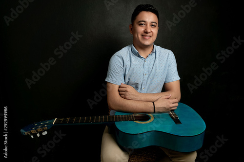 Boy playing acoustic guitar on a bench photo