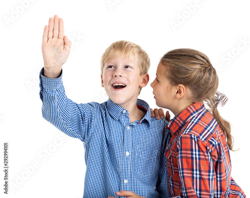 Preteen boy with rised hand and young girl wispering, children in checkered shirts isolated on white background photo