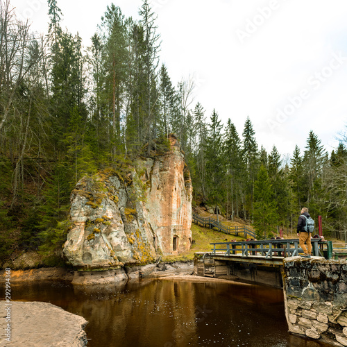 Sandstone rock with ancient chambers and caves reflecting in the river water, Ligatne, Latvia. photo