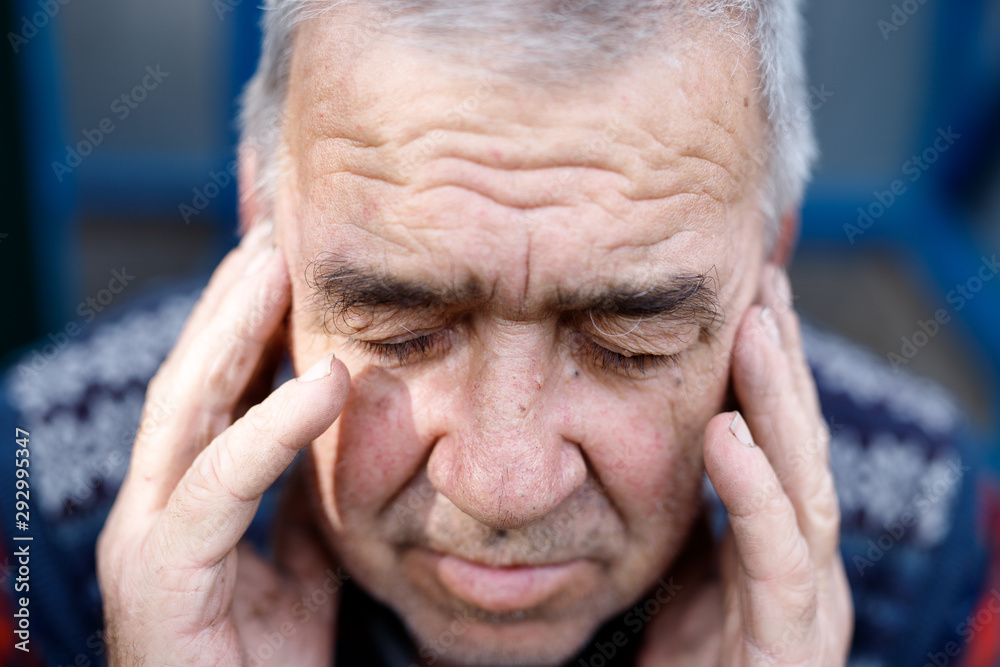 Depressed old man hiding his face behind hands. Adult man has a headache. Depressed old man hiding his face behind hands. Adult man has a headache.