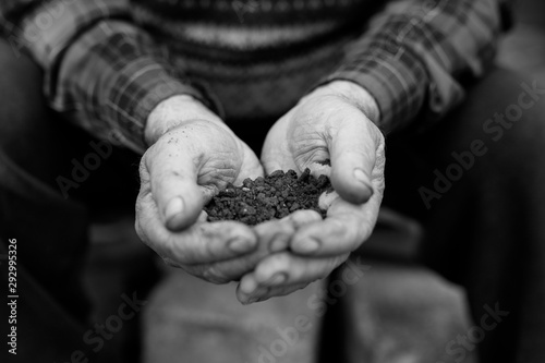 Farmer holding pile of arable soil, male agronomist examining quality of fertile agricultural land. Symbol of spring, gardening season, ecology concept. Earth day.