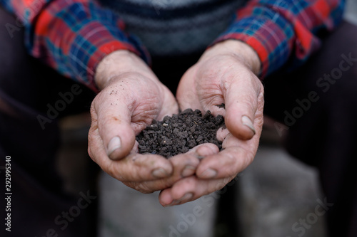 Farmer holding pile of arable soil, male agronomist examining quality of fertile agricultural land. Symbol of spring, gardening season, ecology concept. Earth day.