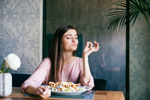 Canvas Print Young lady sitting in a beautiful restaurant, enjoying lunch and gesturing ok si
