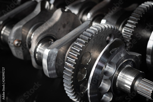 high performance factory racing crankshaft. set on a black reflective background with different lighting.