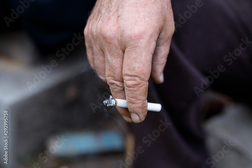 Wrinkled hands of old man with cigarette.