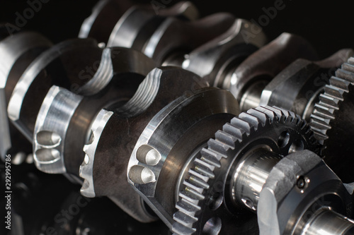 high performance factory racing crankshaft. set on a black reflective background with different lighting.