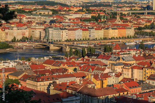 Panoramic view from viewpoint Petrin hill over the rooftops of Prague in district Mala Strana with Vltava and roads, bridge and houses on the shore in sunny day and blue sky