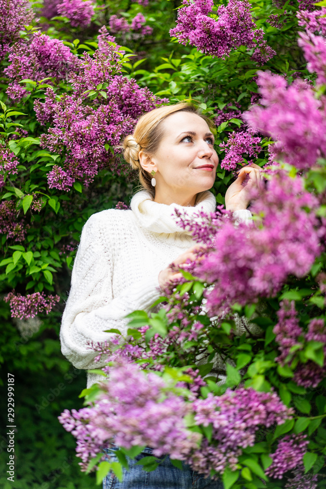Beautiful blond woman posing outdoors at the blur spring park of violet and white lilac background Beautiful blond woman posing outdoors at the blur spring park of violet and white lilac background