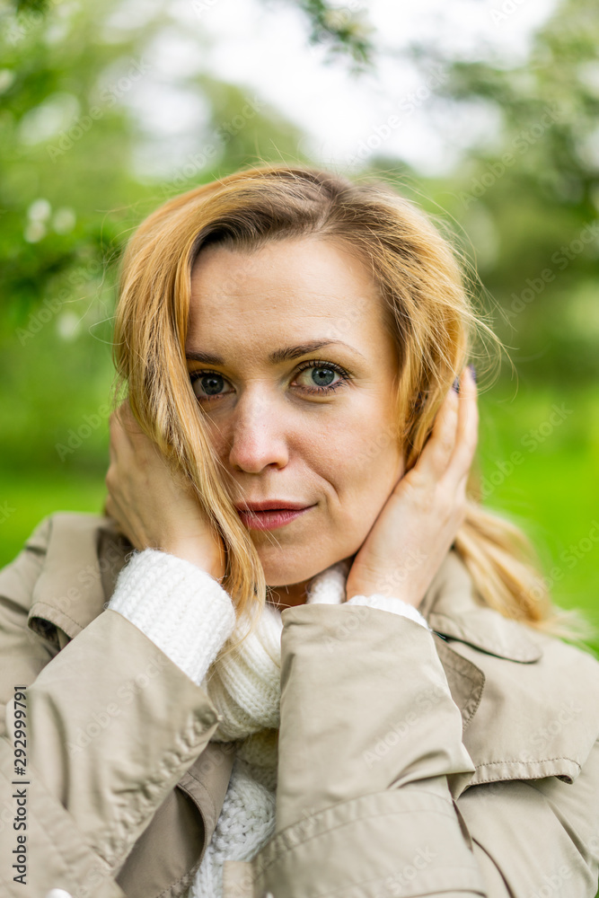 Beautiful blond woman posing outdoors at the blur spring park of violet and white lilac background