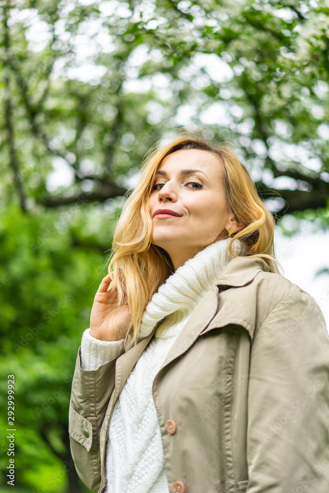 Beautiful blond woman posing outdoors at the blur spring park of violet and white lilac background Beautiful blond woman posing outdoors at the blur spring park of violet and white lilac background