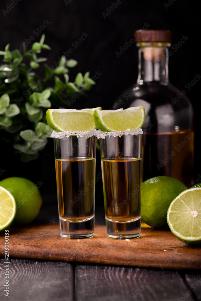 Mexican Gold Tequila with lime and salt on black background with copyspace. Mexican Gold Tequila with lime and salt on black background with copyspace.