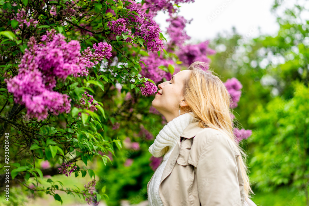 Beautiful blond woman posing outdoors at the blur spring park of violet and white lilac background Beautiful blond woman posing outdoors at the blur spring park of violet and white lilac background
