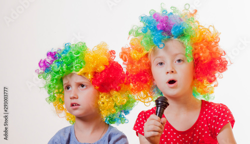 Portrait of little cute caucasian child girls superstars singing with the microphone. Very funny facial expression.