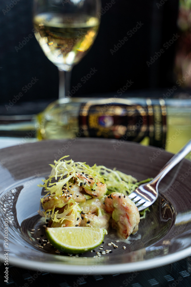 Close up of deep fried prawns with greens and a glass of white wine