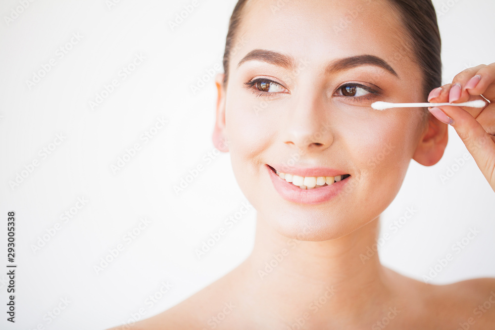 Young woman contouring her eyebrows with cotton swab