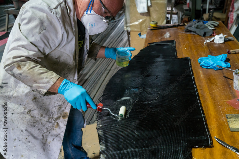 Man with protections on hands, eyes and mask, repairing a piece of carbon and epoxy resin. Man with protections on hands, eyes and mask, repairing a piece of carbon and epoxy resin.