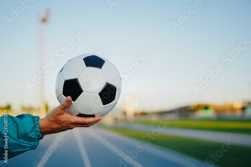 Man's hand holding soccer ball on running track © quemirasbobo
