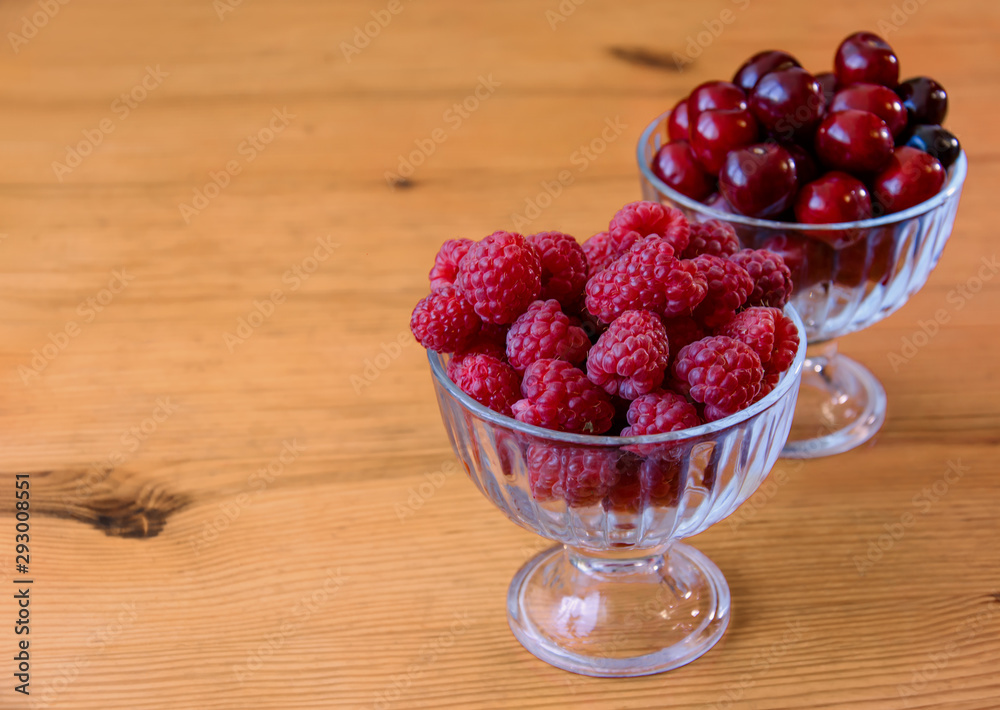 red raspberries and cherries in bulk in glass bowls red raspberries and cherries in bulk in glass bowls