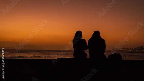 A woman and a man looking the sunset in the sea.