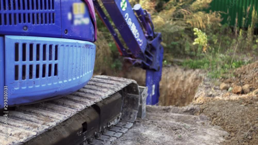 Focus on excavator tracks. Hydraulic digger is digging a hole in the ground for digestion tank at construction site Focus on excavator tracks. Hydraulic digger is digging a hole in the ground for digestion tank at construction site