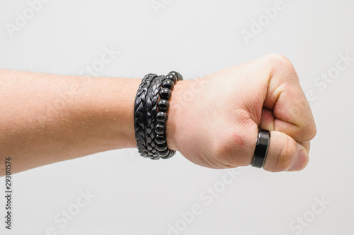 Punch hand. Hand of a white man wearing black accessories with a closed fist giving a punch. Side view, white background.